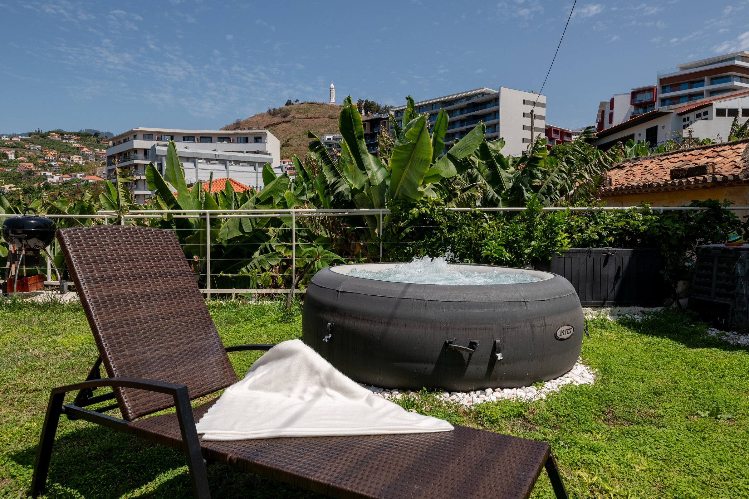 Private jacuzzi and sun lounger on the shared lawn, city view beyond