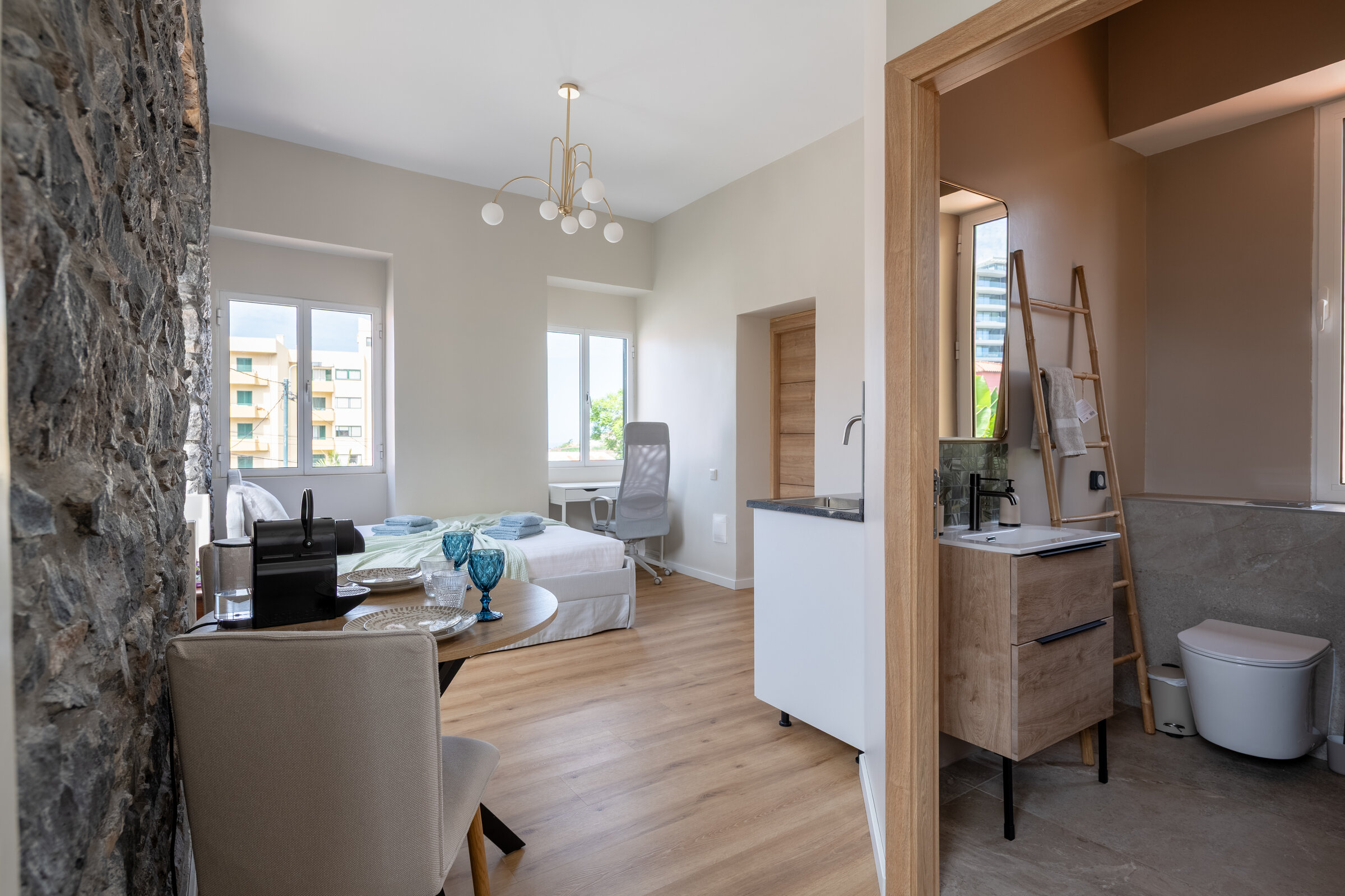 Open-plan studio interior with stone accent wall, living area and kitchenette