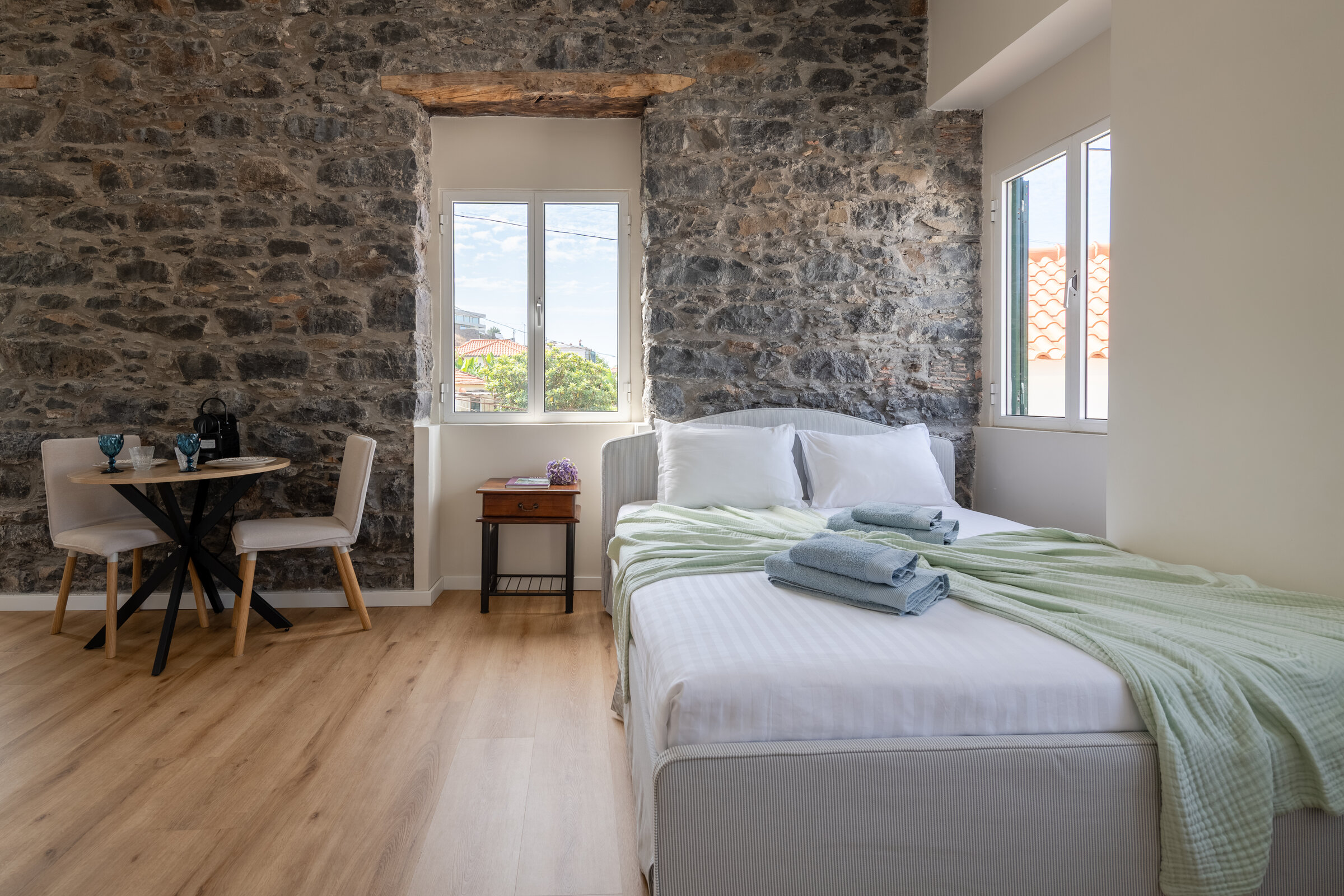 Bedroom with exposed stone wall, dining table and city view