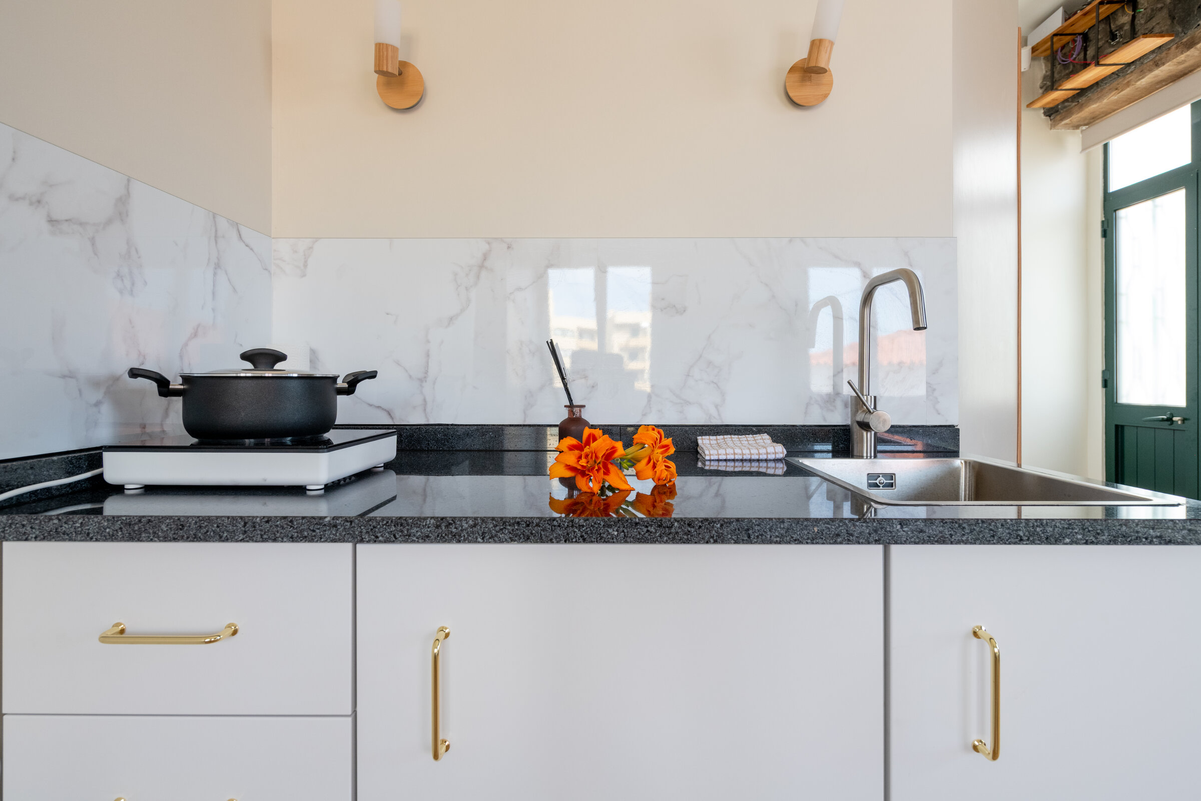 Kitchenette counter with induction hob, sink and fresh flowers