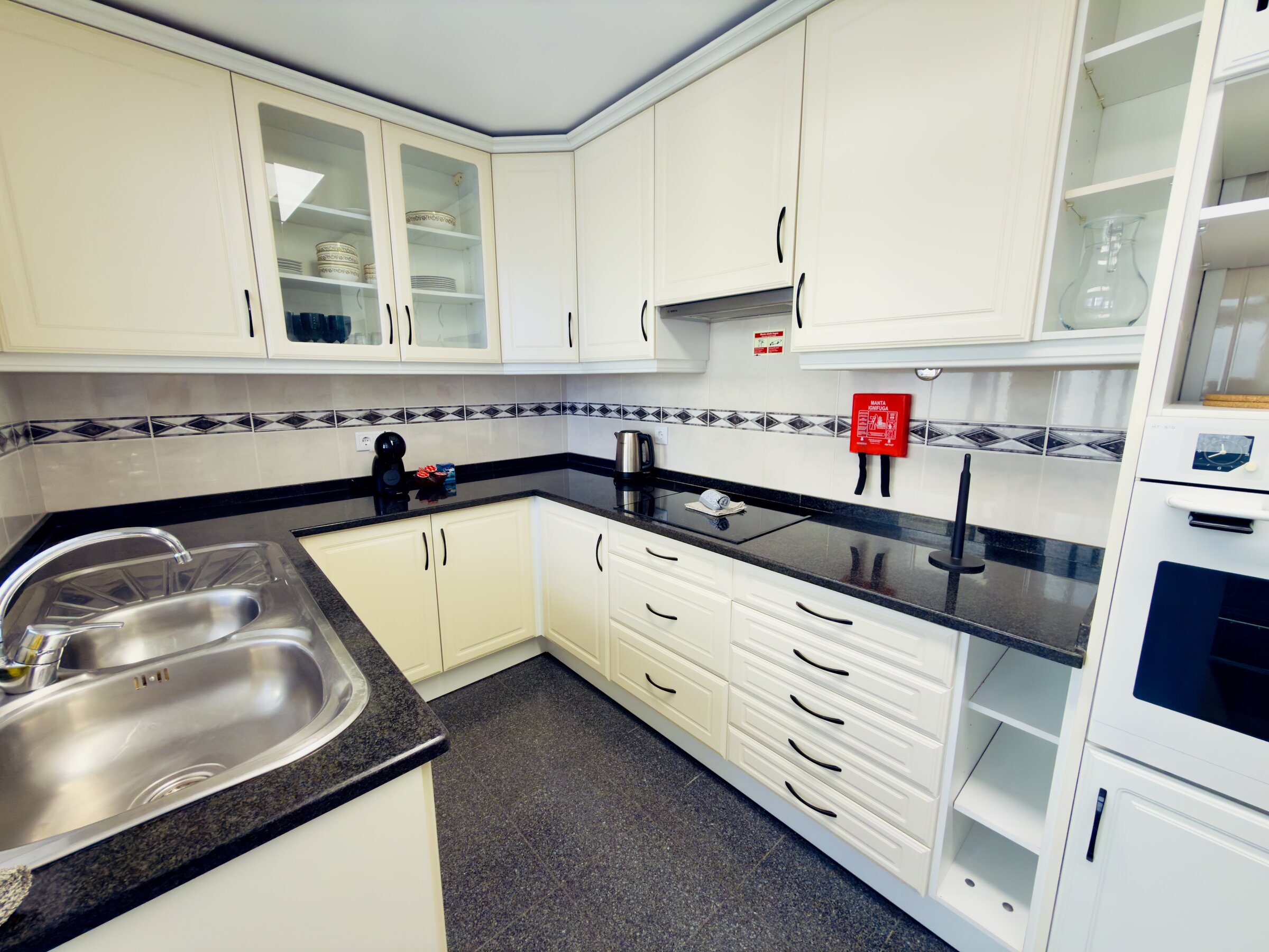 Fully equipped kitchen with white cabinetry and tiled backsplash