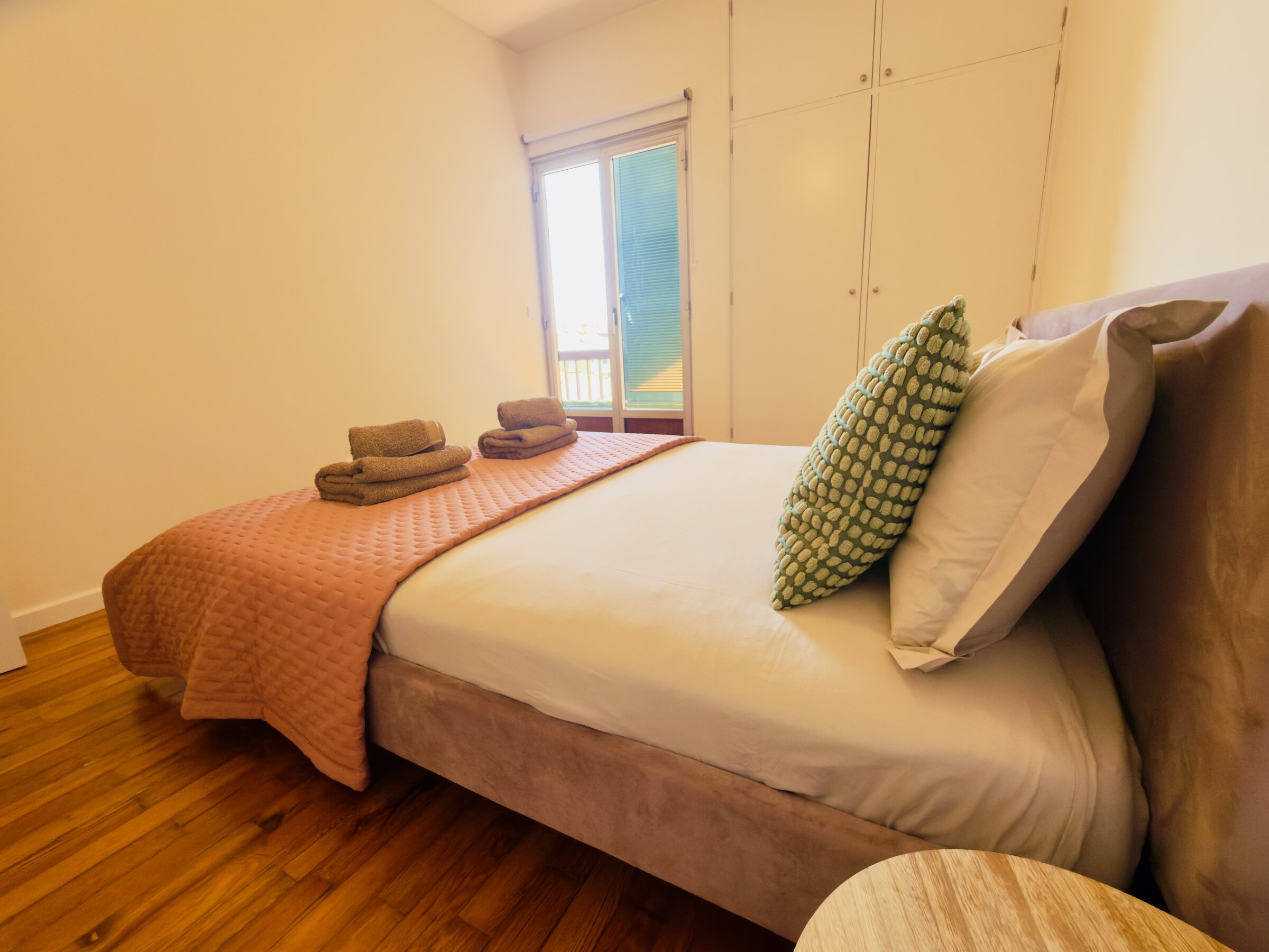 Second bedroom with terracotta bedspread, doors opening onto the balcony