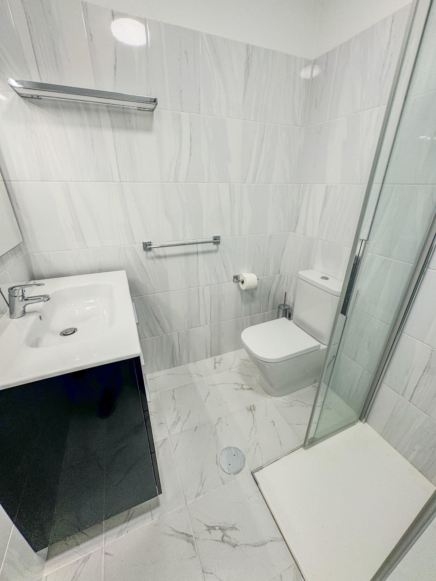 Bathroom with marble-effect tiling and glass shower