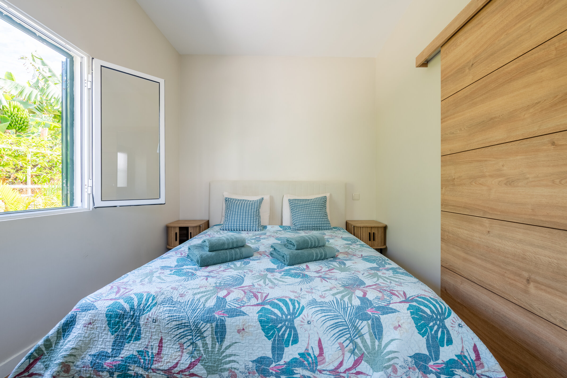 Bedroom with double bed in tropical-print linens and nightstands