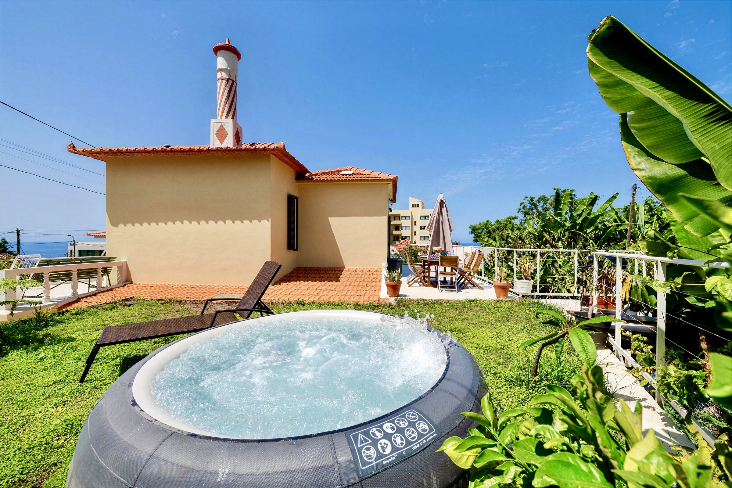 Private jacuzzi bubbling on the lawn, sea and city view beyond